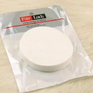 Éponge de maquillage blanche ronde Fair Lady en latex NBR, dans son emballage plastique transparent, posée sur une fausse fourrure beige.