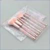Trousse de 7 pinceaux de maquillage avec des manches transparents remplis de paillettes roses et blanches, dans une pochette.
