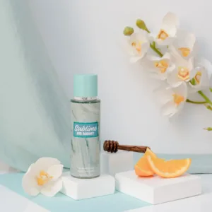 Brume parfumée Rimita Sublime and Radiant!, flacon turquoise entouré d’orchidées blanches, miel et tranches d’orange.