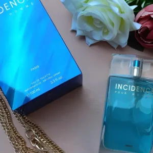 Coffret bleu et flacon Incidence Pour Homme entourés de roses blanches et d'une chaîne dorée décorative.