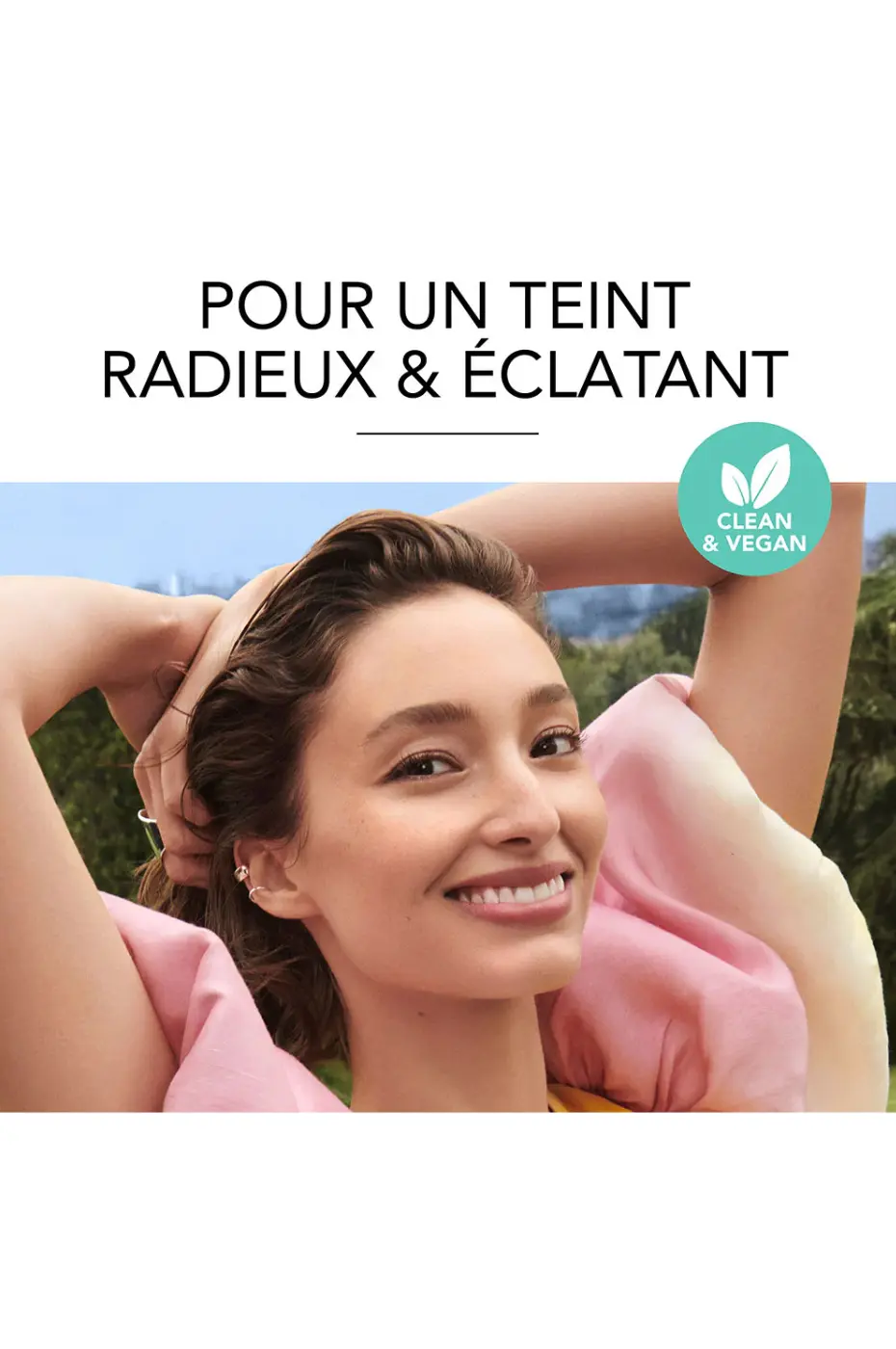Teint Radieux & Éclatant avec Bourjois Clean & Vegan Mannequin souriant en extérieur, teint radieux. Produit Bourjois Clean & Vegan pour un teint éclatant.