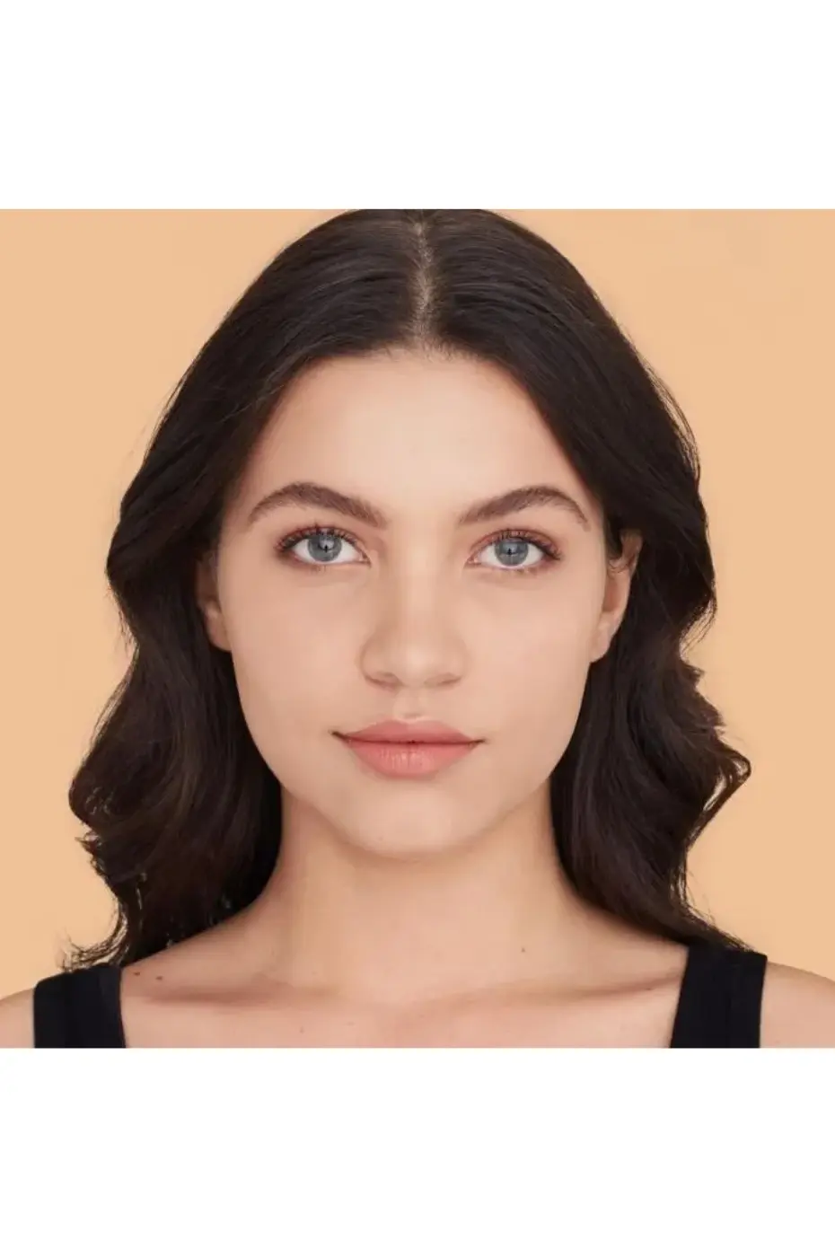Portrait Teint Parfait MAYBELLINE Fit Me! 128 (Mat) Gros plan d'une jeune femme aux cheveux foncés et yeux bleus. Son teint est unifié, lisse et mat, résultat du fond de teint Maybelline Fit Me! 128.