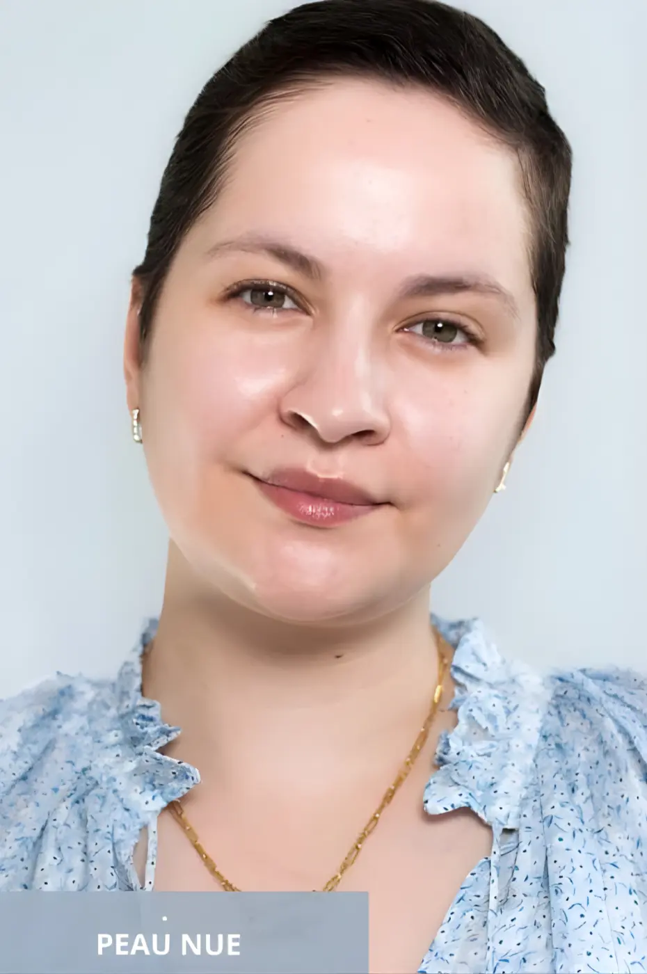 Avant Maquillage : Le Charme d’une Peau Naturelle Portrait de femme souriante, peau nue sans maquillage, cheveux courts, vêtue d'un chemisier bleu à volants.