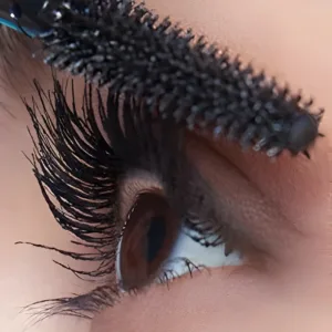 Application du mascara Maybelline Sky High Noir sur des cils longs et volumineux. Gros plan sur la brosse flexible et l'œil marron.