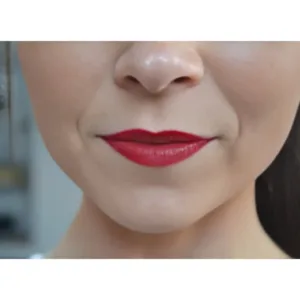 Gros plan sur un sourire subtil, avec des lèvres pulpeuses maquillées d'un rouge intense et lumineux.