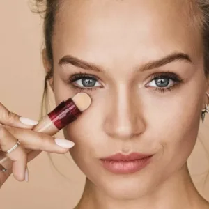 Application du correcteur Maybelline Instant Age Rewind sous l’œil, révélant une texture fluide et un fini naturel.