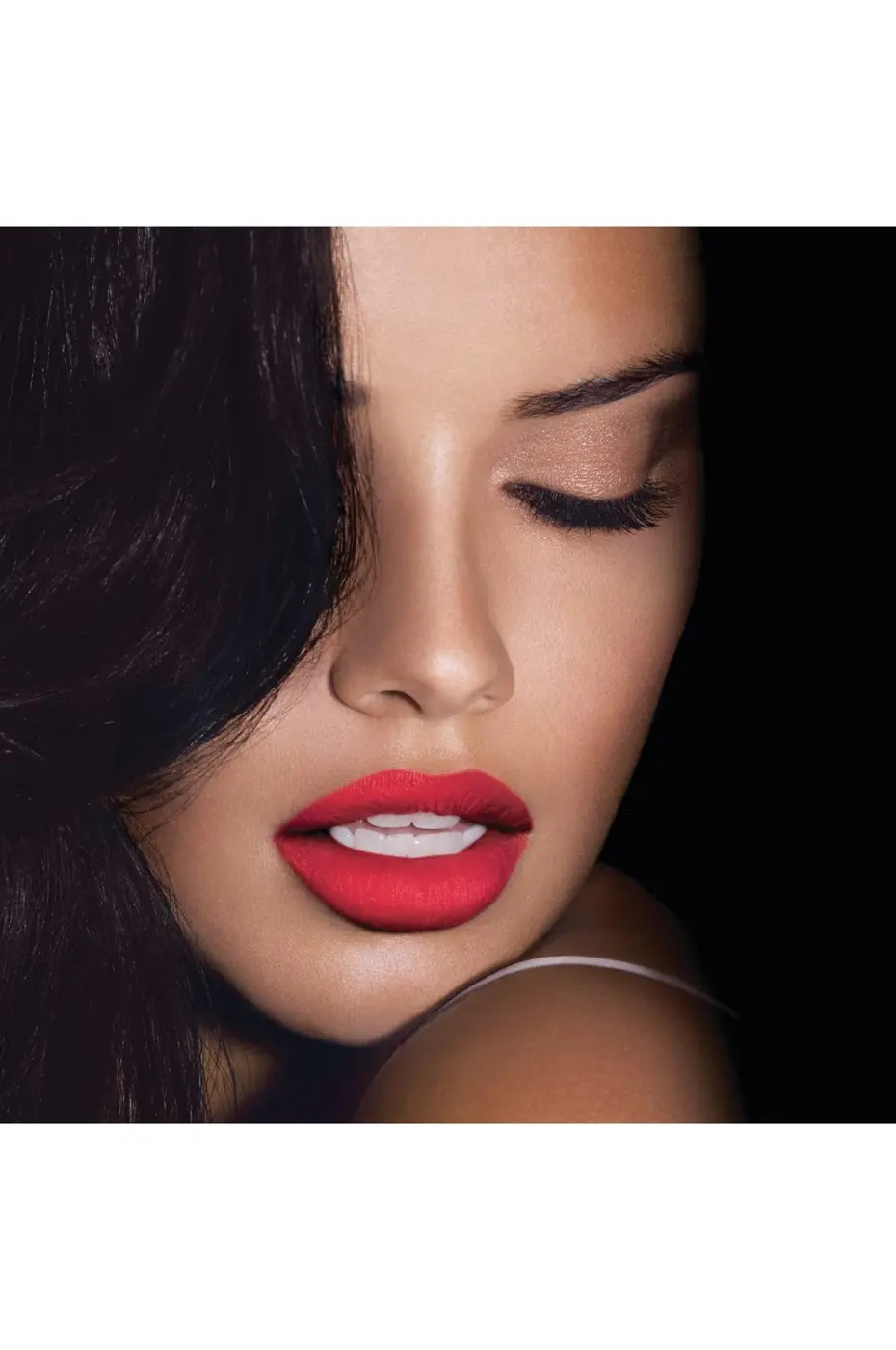 Contraste Glamour Gros plan sur un mannequin aux cheveux noirs, avec un rouge à lèvres Maybelline Mat 965 éclatant et des paupières fermées nude.