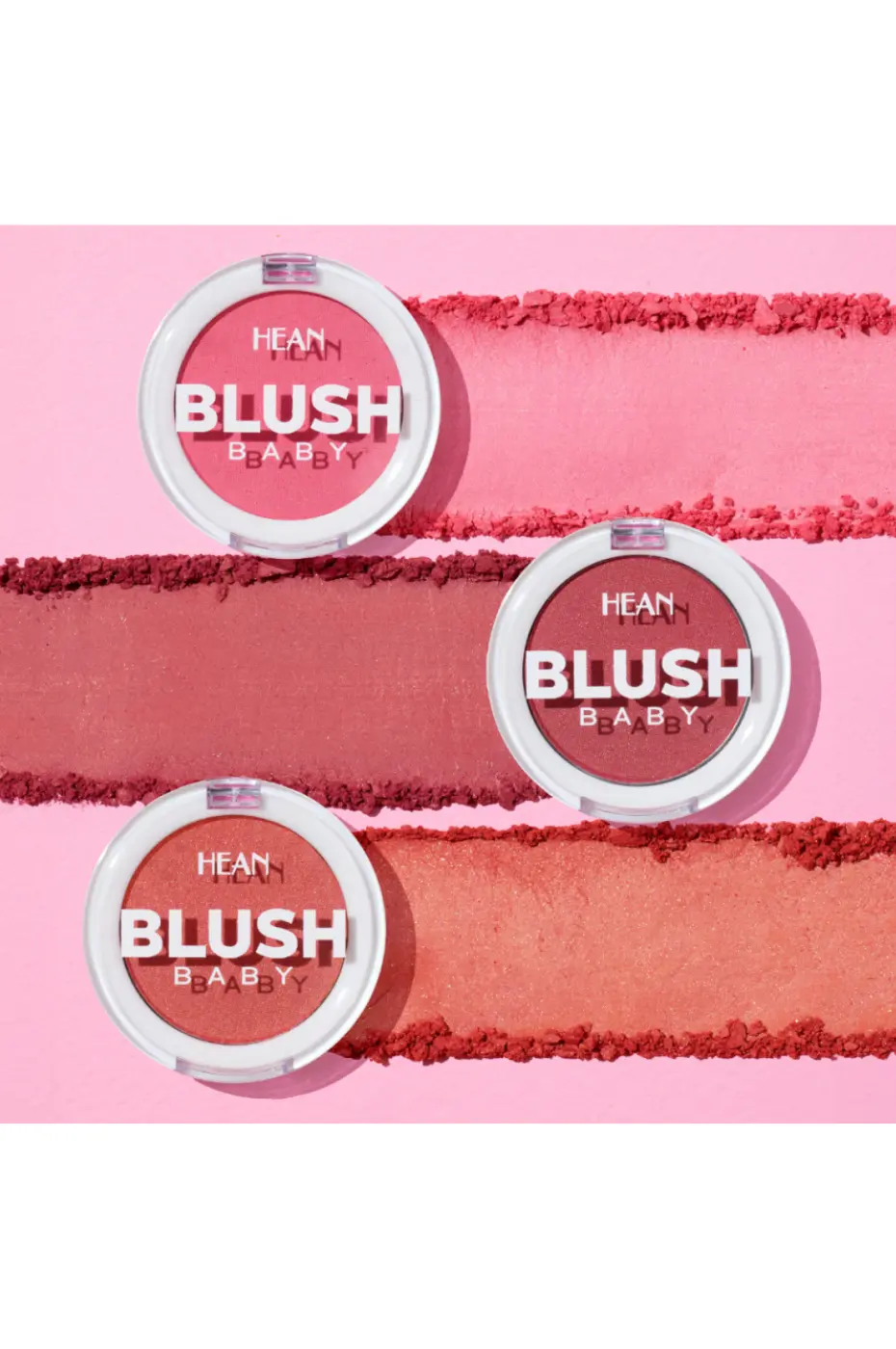 HEAN BLUSH BABY – Aperçu Texturé des Couleurs Gros plan sur trois boîtiers de blush HEAN BLUSH BABY et leurs swatches poudre en arrière-plan, montrant des teintes rose, rouge et corail.
