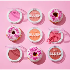 Composition de neuf éléments : six boîtiers de blush HEAN BLUSH BABY et trois mini-beignets décoratifs sur fond rose, évoquant la gourmandise.