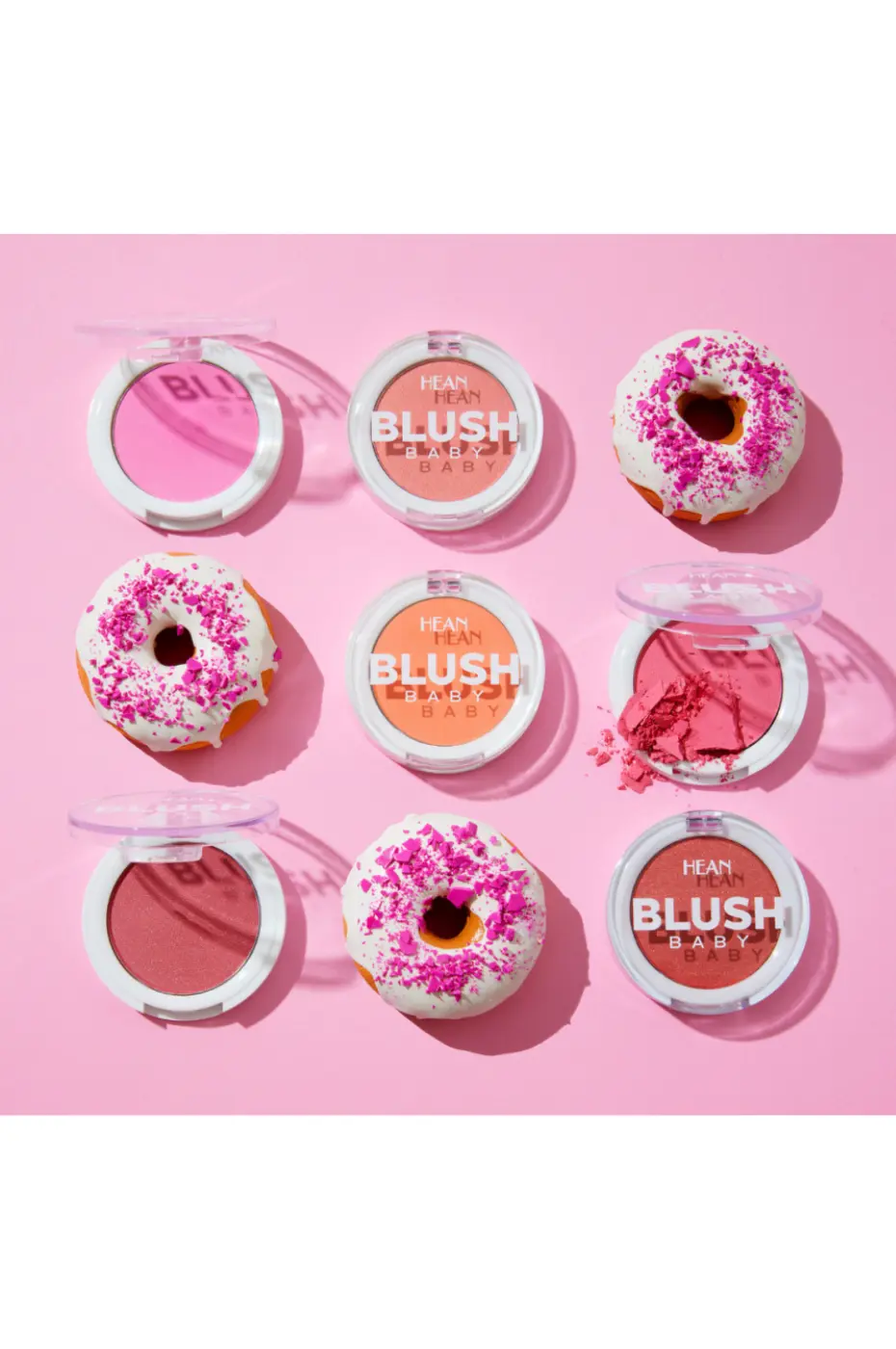 HEAN BLUSH BABY – Douceur et Gourmandise Poudrée Composition de neuf éléments : six boîtiers de blush HEAN BLUSH BABY et trois mini-beignets décoratifs sur fond rose, évoquant la gourmandise.