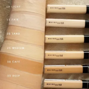 Échantillons de six teintes du correcteur Maybelline Fit Me (10 Light à 35 Deep) sur un bras. Les tubes produits sont alignés à droite.