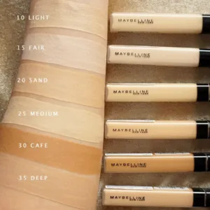 Nuancier de l'anti-cernes Maybelline Fit Me. Six teintes sur l'avant-bras, du 10 Light au 35 Deep, montrant la variété.