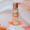 Brume parfumée Rimita Chic and Glam, flacon 200ml orange sur socle blanc avec pétales et fleurs séchées.