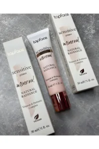 Tube et emballage de la base Topface Sensitive Primer Mineral Natural Radiance 30ml avec logo Vegan sur fond gris texturé.