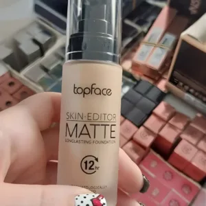 Main tenant un flacon de fond de teint Topface Skin Editor Matte 002, texture fluide, fini matifié et tenue 12h avec SPF 20.
