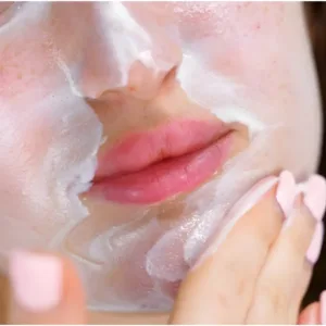 Gros plan d'une femme appliquant le gel-crème nettoyant blanc K-REINE sur son visage pour apaiser les peaux sensibles.