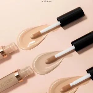 Trois applicateurs d'anti-cerne Elegant Milano N°02 Sand montrant une texture fluide et couvrante sur fond beige.