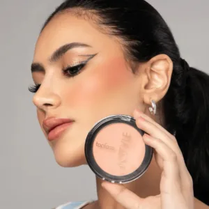 Femme appliquant le fard à joues Topface Instyle N013. Teint naturel, pêche et mat, avec le boîtier compact visible.
