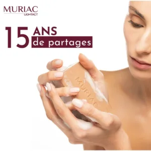 Gros plan des mains tenant le savon Muriac avec le texte "15 ANS de partages", célébrant l'expertise en soins naturels.