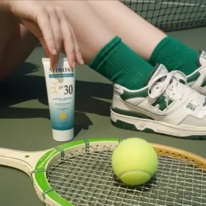 Personne sur un court de tennis avec une raquette, tenant le tube MIROSA SPF 30. Ambiance dynamique et ensoleillée.