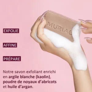 Savon exfoliant Muriac à l'argile blanche et noyaux d'abricot, tenu à la main avec une mousse fine et onctueuse.