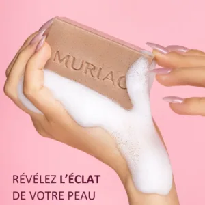 Savon exfoliant Muriac Lightact tenu à la main avec une mousse onctueuse, révélant l'éclat de la peau.