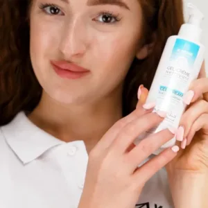 Jeune femme tenant le flacon K-REINE et appliquant la texture onctueuse du gel-crème sur son visage pour apaiser sa peau.