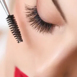 Goupillon Pollié approchant des cils supérieurs pour séparer les poils et éliminer les paquets de mascara efficacement.