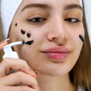 Jeune femme déposant des touches de gel nettoyant noir sur son visage avec le flacon pompe pratique de K-REINE.