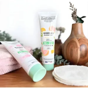 Gommage Énergisant Agrumes et Masque Repulpant Evoluderm sur un plan de travail avec serviette et cotons démaquillants.