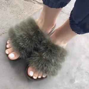 Gros plan de pieds féminins avec une pédicure blanche impeccable, portant des sandales à double bride en fourrure verte.