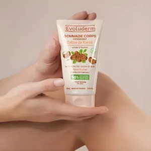 Gommage corps hydratant Evoluderm Délice de Karité 150ml, tube tenu à la main sur une jambe, soin exfoliant peaux sèches.