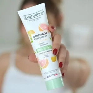 Main présentant le tube de Gommage Énergisant Agrumes Evoluderm, certifié végan et formulé à 98% d’origine naturelle.
