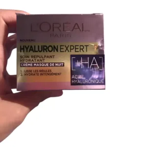 Boîte de crème de nuit L'Oréal Hyaluron Expert tenue à la main, soin hydratant à l'acide hyaluronique pour lisser la peau.