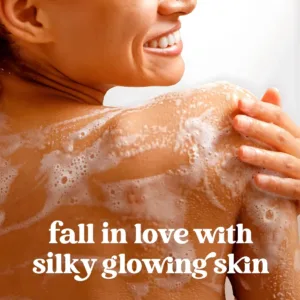 Femme souriante de dos avec mousse de gel douche sur l'épaule, texte "fall in love with silky glowing skin". Marketing soin corps.