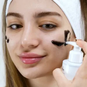 Application délicate du gel purifiant K-REINE au charbon sur le visage pour un moment de soin et de douceur quotidien.