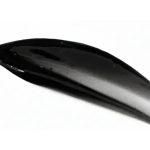 Texture onctueuse et brillante d’un gel nettoyant noir intense infusé au charbon actif sur un fond blanc épuré.
