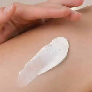 Texture onctueuse du gommage corps au karité Evoluderm avec grains exfoliants de poudre de noix, appliquée sur la peau.