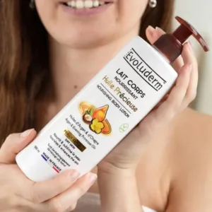 Flacon d'huile précieuse et lait corps nourrissant Evoluderm aux huiles d'argan et d'onagre tenu à deux mains.