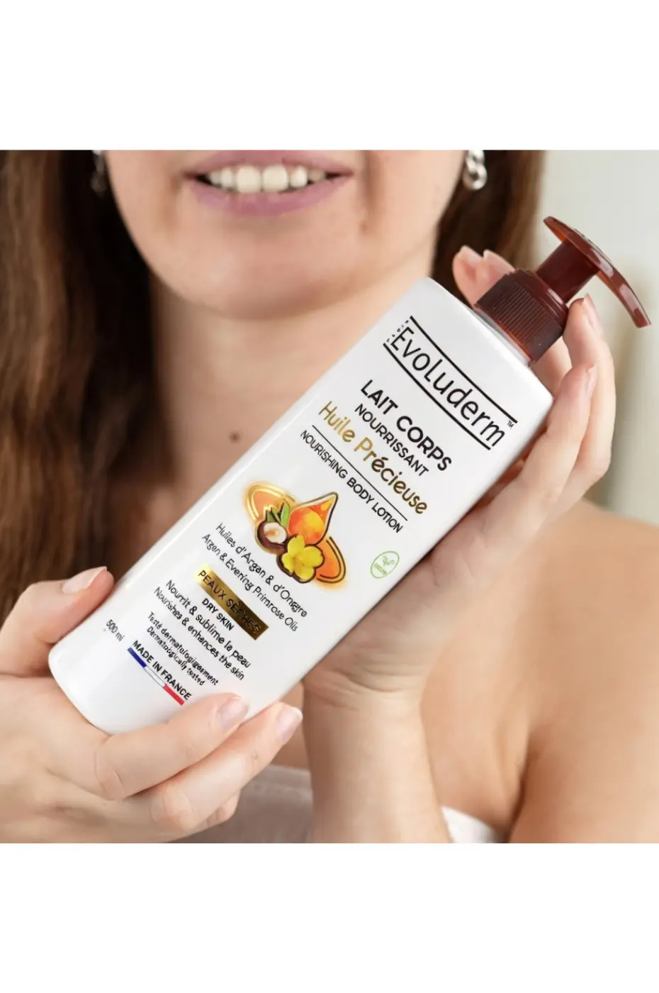 evoluderm-lait-corps-huile-precieuse-2 Flacon d'huile précieuse et lait corps nourrissant Evoluderm aux huiles d'argan et d'onagre tenu à deux mains.