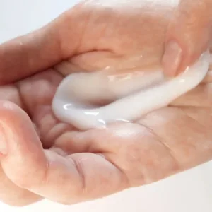 Lait corps hydratant Evoluderm Huile Précieuse étalé au creux d'une main pour une application soin de la peau quotidienne.