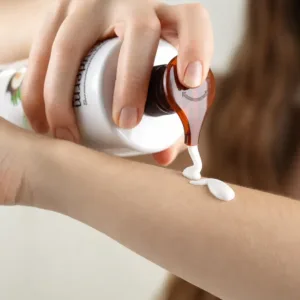 Application du lait corps hydratant Evoluderm Huile Précieuse avec flacon pompe sur l’avant-bras pour nourrir la peau.