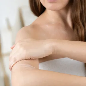 Une femme applique le lait corps hydratant Evoluderm Huile Précieuse sur son bras pour nourrir sa peau au quotidien.