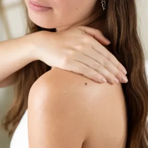 Femme appliquant le lait corps Evoluderm Huile Précieuse sur son épaule pour hydrater sa peau au quotidien.