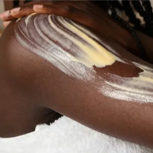 Application du lait corps Evoluderm à la carotte sur une peau noire pour l'hydrater et illuminer le teint naturellement.