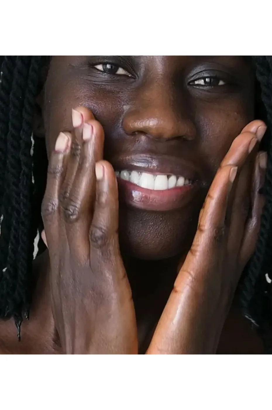evoluderm-lait-de corps-carotte-vitaminee-5 Une femme à la peau noire applique du soin hydratant Evoluderm à la carotte sur son visage radieux en souriant.