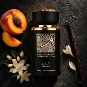 Flacon noir Fakhar Thameen Collection entouré d'une pêche coupée, de fleurs blanches d'oranger et d'une gousse de vanille.
